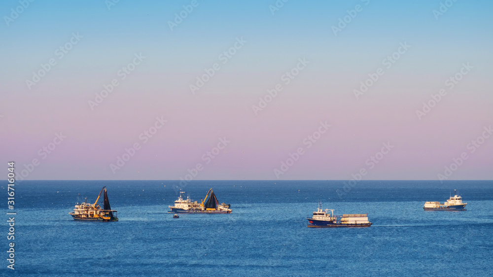 Fishing trawlers at the blue sea catching a fish