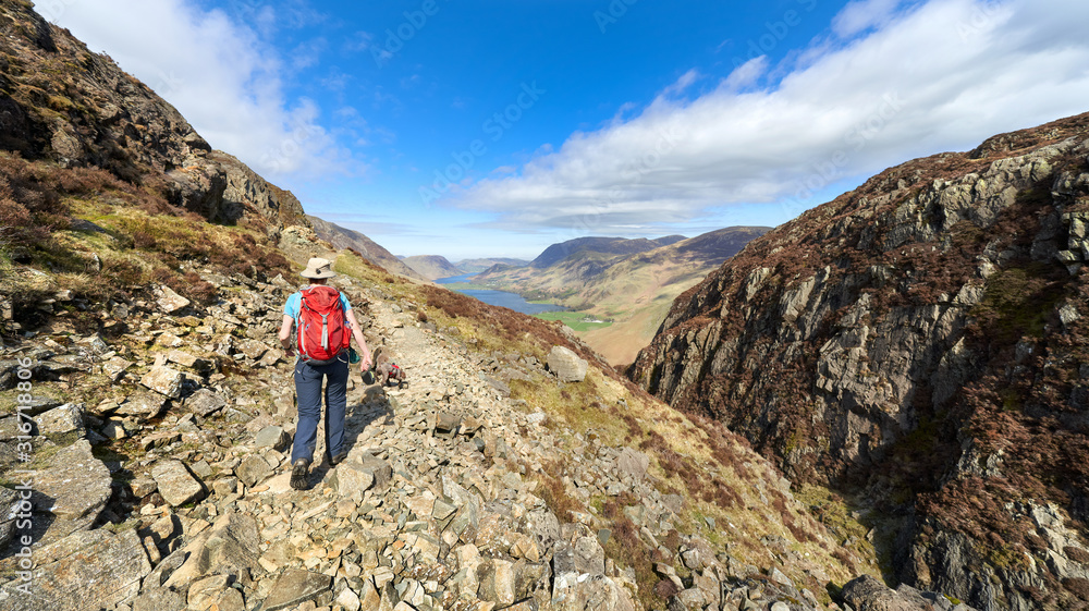A female hiker Ascending Hay Stacks with Green Crag on the left on a sunny spring day in the Lake District.