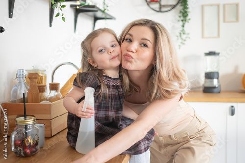 Young mother making domestic work at kitchen with her toddler daughter. Domestic life