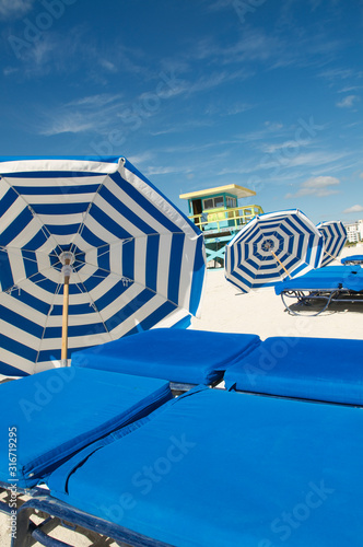 Blue and white striped umbrellas resting next to sunbeds on Miami Beach