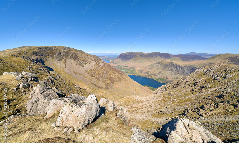 Views of High Stile, Eagle Crag and Grey Crag on the left with Grasmoor and Robinson in the distance above Buttermere on a sunny day in the Lake District.