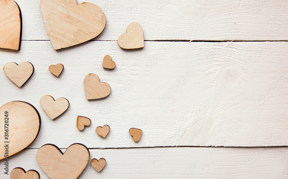 Fototapeta premium A beautiful background with lot of wooden hearts on the white table