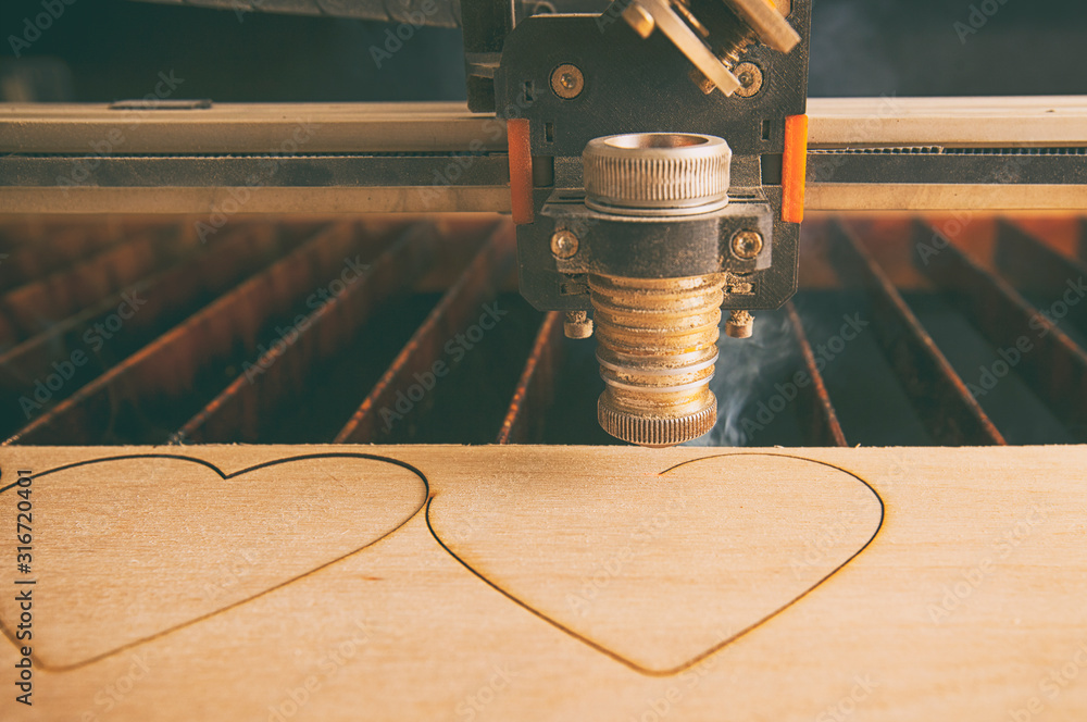 Laser cutting machine is cutting hearts in the wooden plank