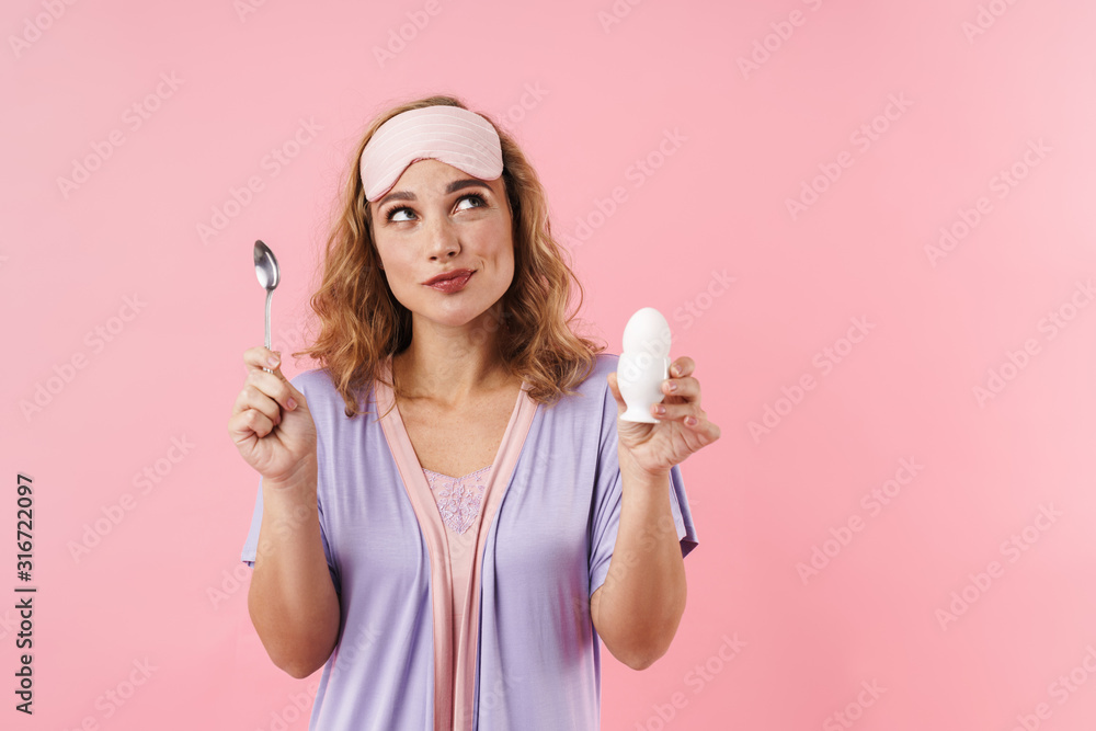 Image of young woman looking upward while holding egg and spoon Image of young woman looking upward while holding egg and spoon