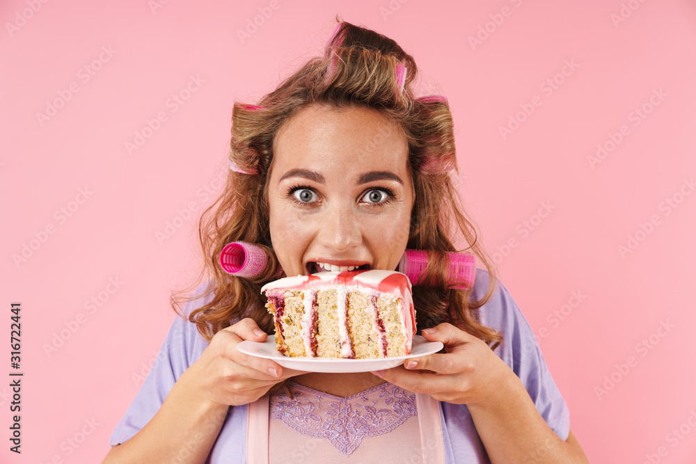 Image of young happy woman looking at camera and eating cake