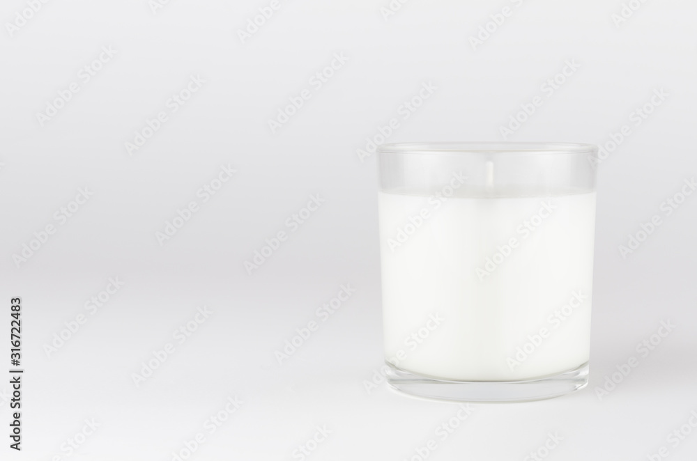 White candle in transparent glass on white background, mock up for branding identity product, advertising, presentation, design of packing. White candle in transparent glass on white background, mock up for branding identity product, advertising, presentation, design of packing.