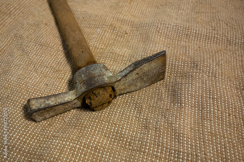 Miner hammer like pickaxe or mattock on bagging fabric background. Closeup view of rustic old hand tool for hard working to extract fossils or concept of block chain currency mining photo