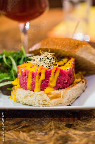 Burger with Steak tartare made from raw ground  beef and  served with a raw egg yolk sauce