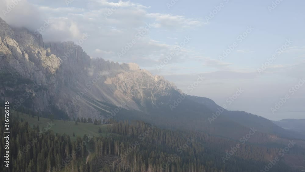 Aerial view of Dolomites. Geisler or Odle Dolomites Group. Drone flies above fir tree tops, chopped trees to mountains peak. Rural landscape. Summer. South Tyrol, Italy. Pan left to right Aerial view of Dolomites. Geisler or Odle Dolomites Group. Drone flies above fir tree tops, chopped trees to mountains peak. Rural landscape. Summer. South Tyrol, Italy. Pan left to right