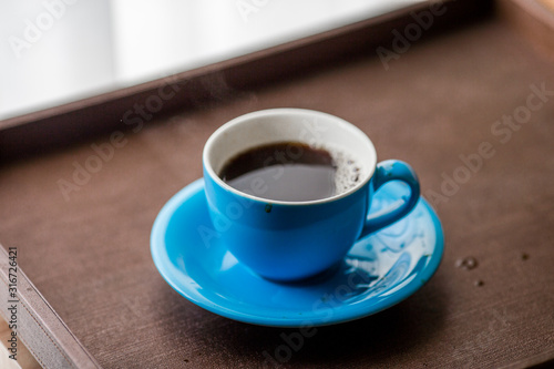 Close-up view of the blue coffee mug, clear glass for drinking water, placed on a tray to bring clear drinks, seen at resorts, hotels or bakeries