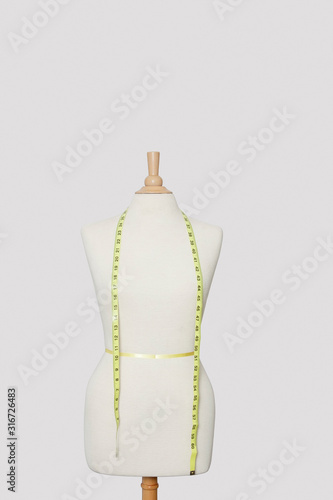 Measuring tape on dressmakers model over colored background