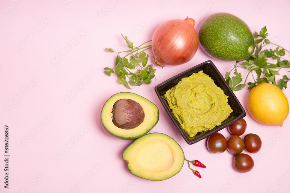 Guacamole en un bol con ingredientes sobre fondo rosa pastel. Guacamole en un bol con ingredientes sobre fondo rosa pastel.