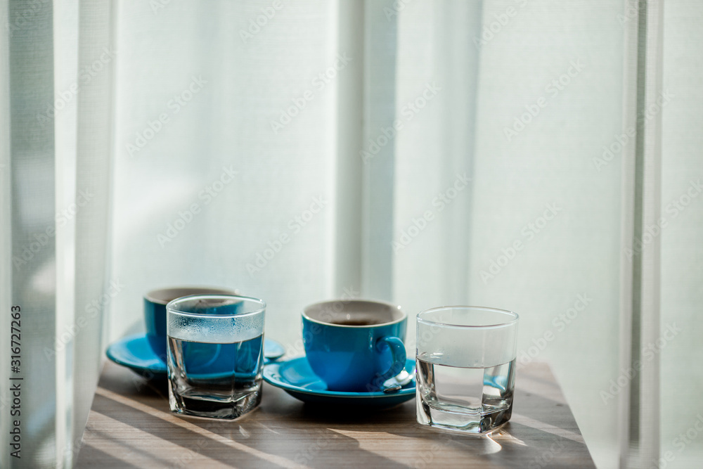 Close-up view of the blue coffee mug, clear glass for drinking water, placed on a tray to bring clear drinks, seen at resorts, hotels or bakeries Close-up view of the blue coffee mug, clear glass for drinking water, placed on a tray to bring clear drinks, seen at resorts, hotels or bakeries