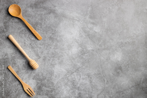 Top view of wooden spoon fork and honey sticks on cement background.