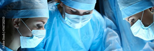 Group of surgeons at work operating in surgical theatre