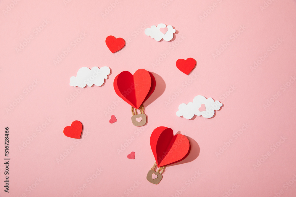 top view of paper heart shaped air balloons in clouds on pink top view of paper heart shaped air balloons in clouds on pink