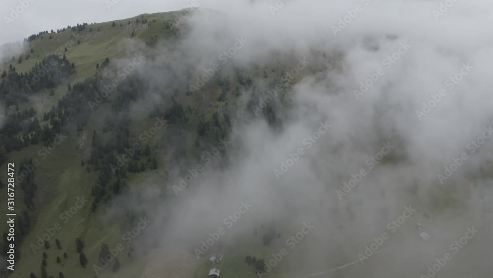 Aerial view of wooded hills with pine trees, spruces. Drone flies above tree tops, through clouds. Geisler or Odle Dolomites Group. Alps mountains, South Tyrol, Italy. Aerial view of wooded hills with pine trees, spruces. Drone flies above tree tops, through clouds. Geisler or Odle Dolomites Group. Alps mountains, South Tyrol, Italy.