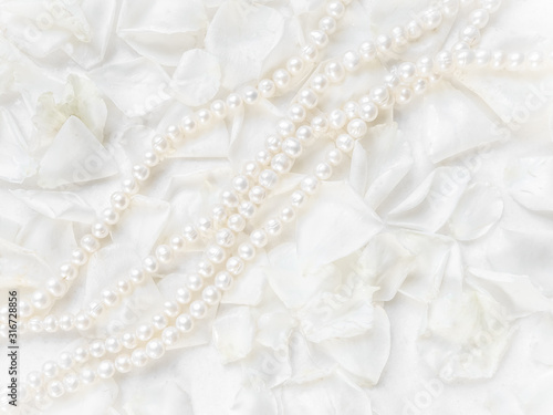Pearl necklace on a background of white rose petals. Ideal for greeting cards for wedding, birthday, Valentine's Day, Mother's Day