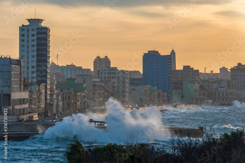 sunset cityscape with big waves at the malecon in havana with buildings and the sea, cuba  photo