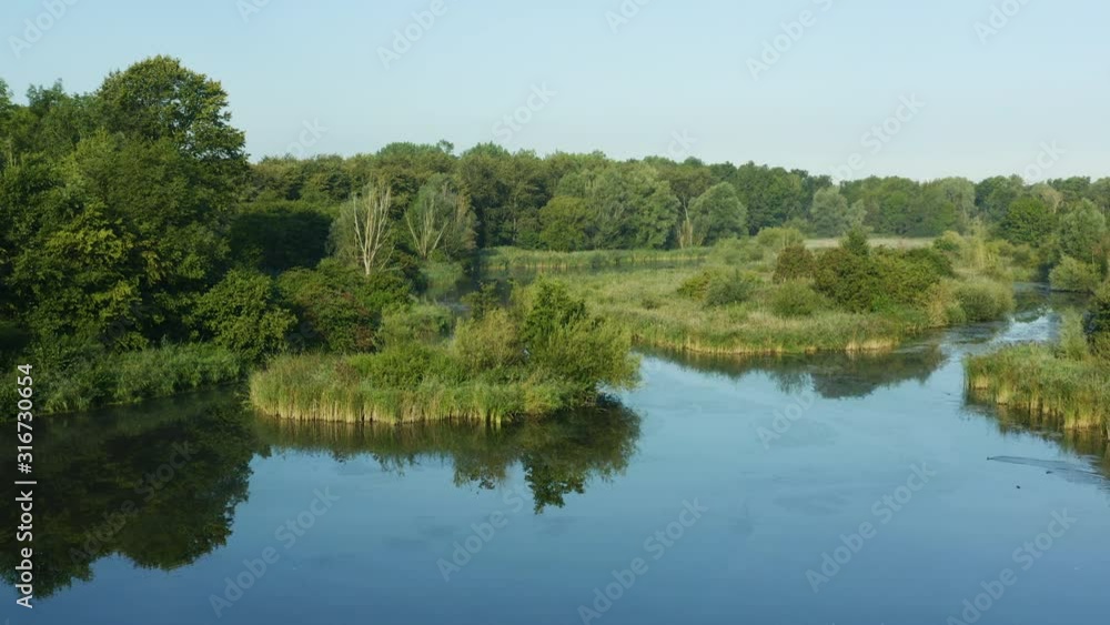 Low aerial orbit view of waterways in a nature reserve in the Netherlands, rising jib shot of a lake and forest. Low aerial orbit view of waterways in a nature reserve in the Netherlands, rising jib shot of a lake and forest.