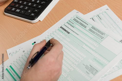 a woman's hand filling out a tax declaration photo