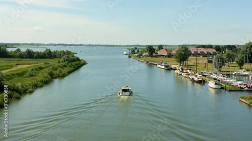 Aerial tracking shot of a boat on the a river sailing towards a lake in Freisland, Holland photo