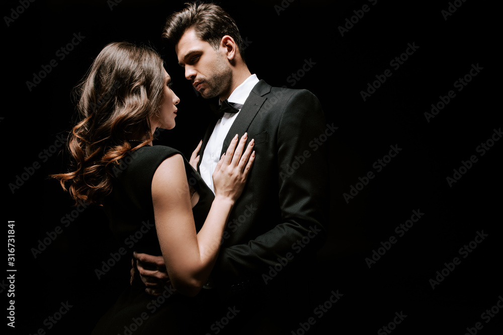 beautiful woman looking at handsome man in suit isolated on black beautiful woman looking at handsome man in suit isolated on black