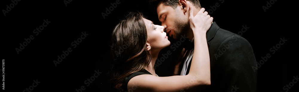 panoramic shot of attractive woman kissing with man isolated on black panoramic shot of attractive woman kissing with man isolated on black