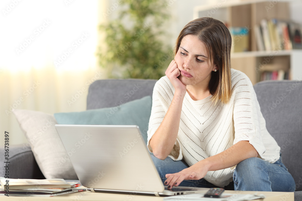Bored woman checking laptop online content at home Bored woman checking laptop online content at home