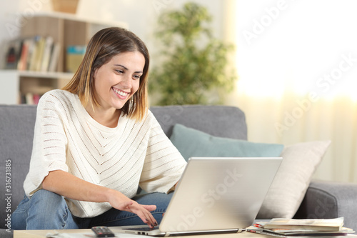 Happy woman checking laptop online content at home photo