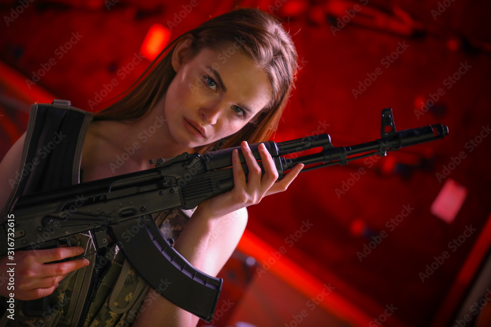 Beautiful girl with guns in hands in a gun shop. Stock Photo Adobe Stock