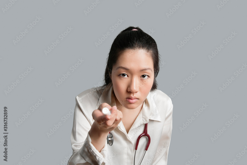 Young Asian female doctor holding a flashlight over gray background Young Asian female doctor holding a flashlight over gray background
