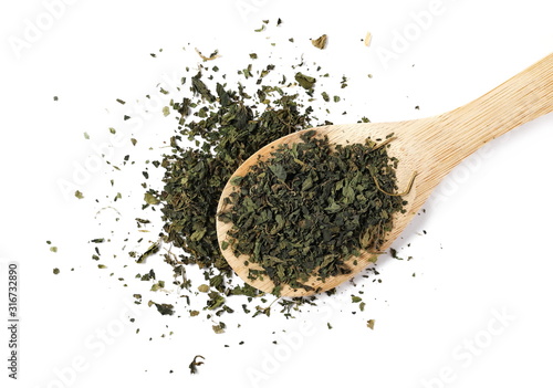 Cut, chopped dry nettle pile with wooden spoon isolated on white background, top view