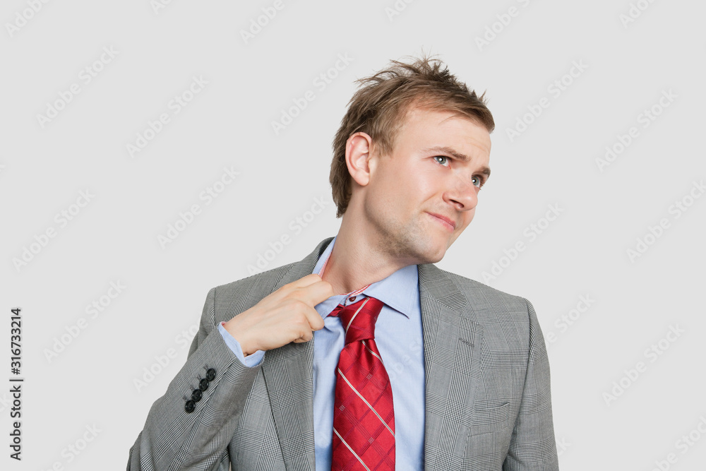 Tired young businessman loosening tie over colored background Tired young businessman loosening tie over colored background