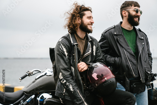 Photo of bearded joyful men bikers smiling and talking photo