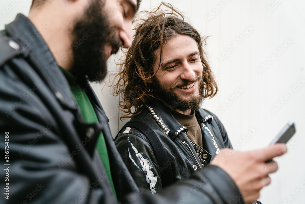 Photo of bearded joyful men bikers using cellphone and smiling Photo of bearded joyful men bikers using cellphone and smiling