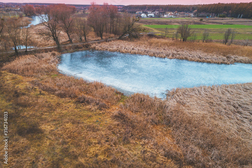 View from above of countryside and frozen brook. Rural nature landscape. Early spring