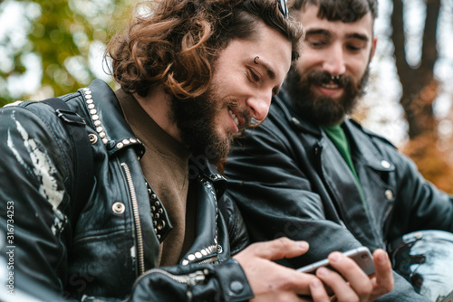 Canvas-taulu Photo of handsome joyful men smiling and using cellphone