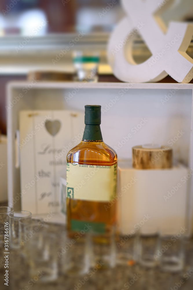 Bottle of cold vodka and wine bottle in bucket with ice and orange juice in jug on table, copy space. Alcohol bottles in ice bucket in restaurant. Wedding party. Bottle of cold vodka and wine bottle in bucket with ice and orange juice in jug on table, copy space. Alcohol bottles in ice bucket in restaurant. Wedding party.