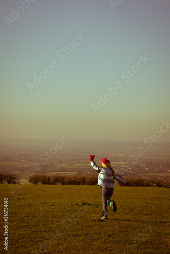 Child flying a kite outdoors on a sunny clear day in a country field