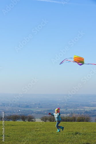 Child flying a kite outdoors on a sunny clear day in a country field
