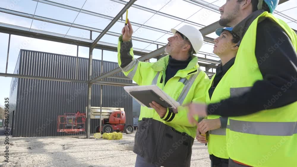 Engineering instructor working on building site with apprentice