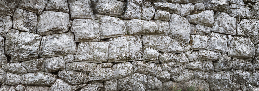 Old stone wall - ancient masonry with a hewn texture of a stonewall background. Old stone wall - ancient masonry with a hewn texture of a stonewall background.