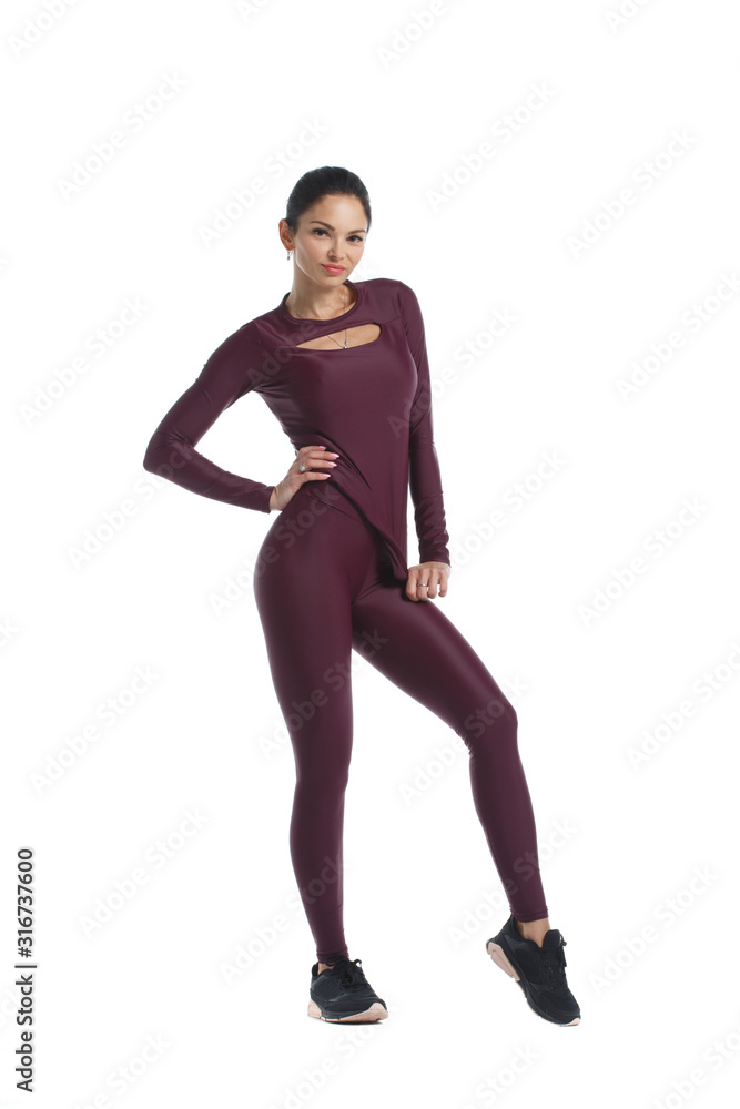 Slender woman in burgundy sportswear stands isolated on a white background.