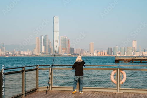 fisher man with fishing rod on coast with HongKong skyline
