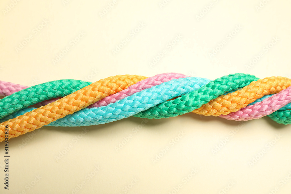 Twisted colorful ropes on beige background, top view. Unity concept Twisted colorful ropes on beige background, top view. Unity concept