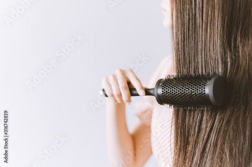 girl combing her hair isolated on a gray background.  beauty concept. copy space