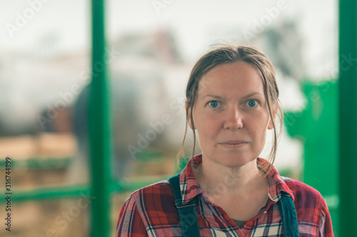 Billede på lærred Portrait of female rancher at horse stable looking at camera