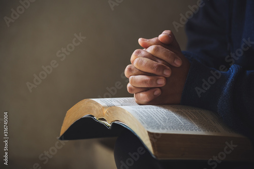 Canvas Print Hands folded in prayer on a Holy Bible in church concept for faith