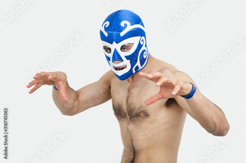 Portrait of a shirtless man in wrestling mask gesturing over gray background photo